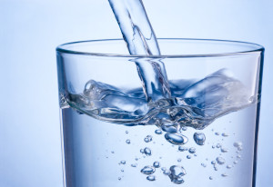 Close up pouring water into glass on a blue background