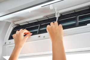 A woman cleaning the filter of an air conditioner