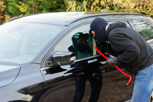 Burglar trying to break into a black car