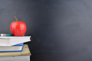Classroom concept with books an apple and blackboard with handwriting