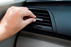 Hand adjusting air conditioner in car