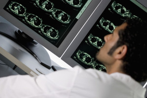 Male doctor examining a CAT scan monitor