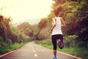 Young fitness woman runner running at forest trail