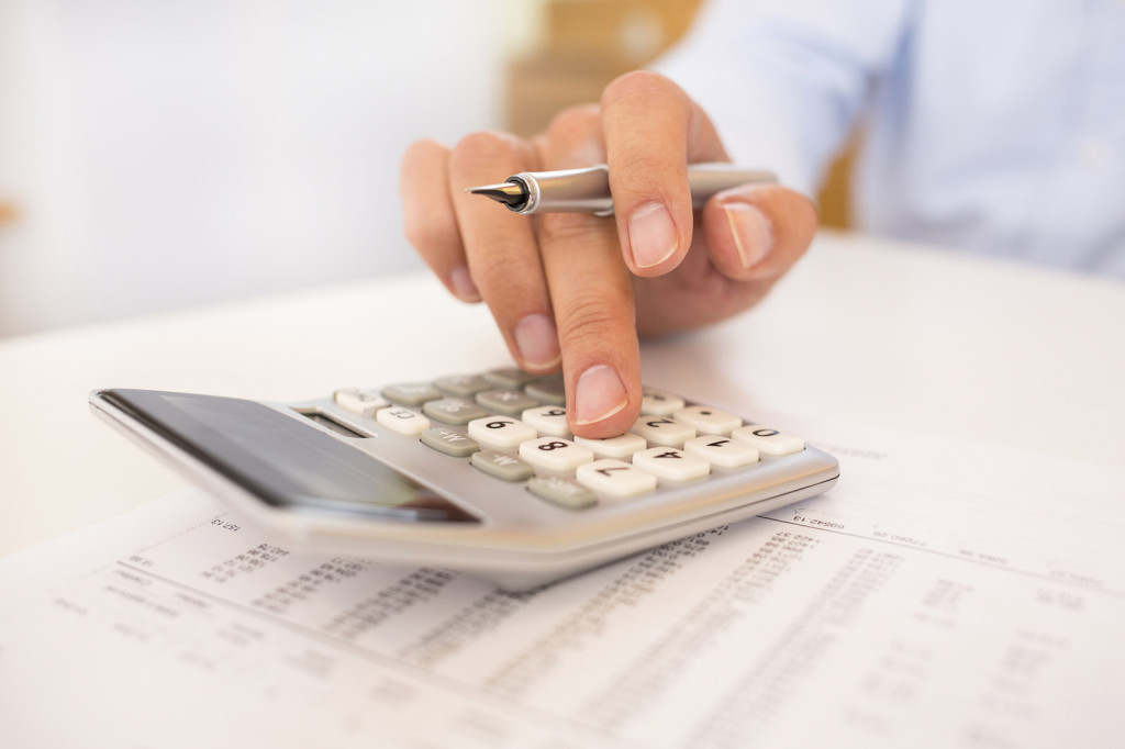 A close up of a man doing accounting work on a calculator