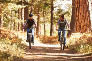 Couple mountain biking through forest, California