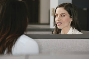 Businesswoman talking to coworker over cubicle wall