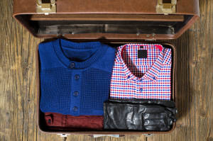 Open travel suitcase with casual man clothes