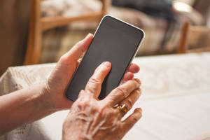 Close up of a wrinkled finger touching a smartphone.