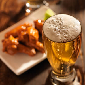 Beer with chicken wings in background.