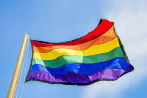Gay rainbow flags waving over blue sky background