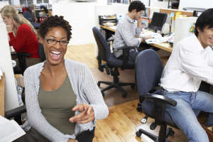 Group of office workers at desks, woman laughing