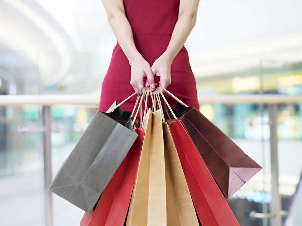 Young woman carrying paper shopping bags in modern mall