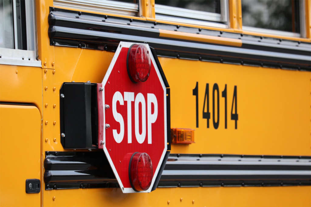Stop sign on the side of a school bus.