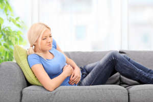Woman with stomach pain sittin on sofa
