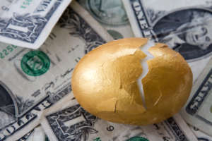 Golden egg with cracked shell on money