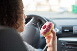 Woman eating a sweet driving a car