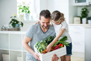 Father and daughter with vegetable box in kitchen