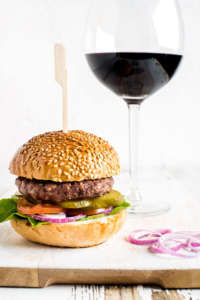Fresh homemade burger on white wooden serving board with onion