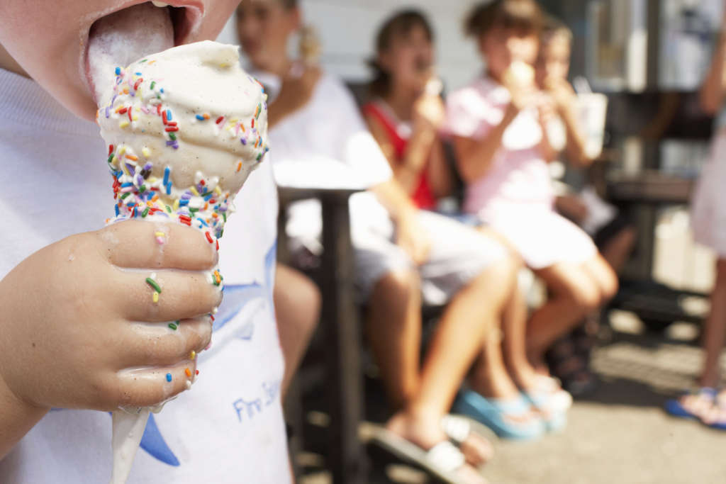 Boy (2 4) licking ice cream, close up, other children in background
