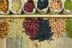 Different kinds of beans scattered on wooden background