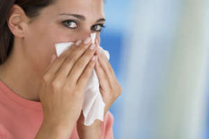 Woman blowing nose into tissue
