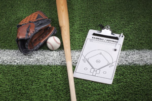 Baseball mitt, bat and clipboard on grass with stripe