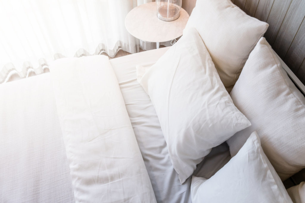 Bed maid up with clean white pillows and bed sheets in beauty room. Close up. Lens flair in sunlight.