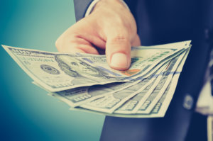 Hand giving money, US dollar (USD) bills vintage tone