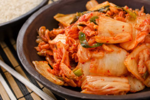 Plate full of kimchi and chopsticks on side