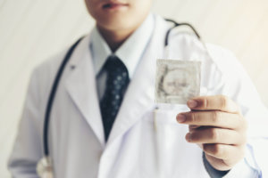 Doctor is holding condom for safe sex protection concept.To prevent the disease called "HIV".