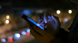 Young pretty woman using smartphone in the city at night