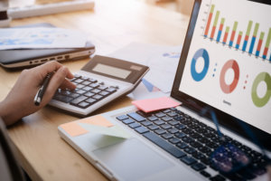 Business woman uses a calculator to calculate the company's performance figures, graphs the monthly graphs for the meeting.