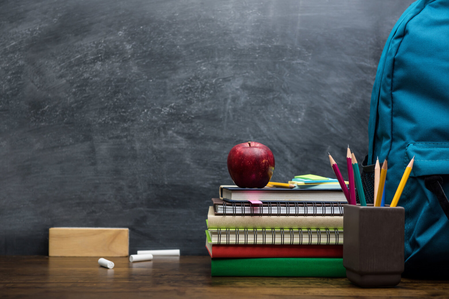 Stack of books, stationery and education supplies on wooden desk