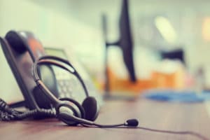 Close up focus on call center headset device headset VOIP system with telephone answer machine technology at operation office desk for hotline telemarketing and network operator concept