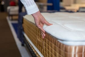 Close up of female hand touching and testing mattress in a store.