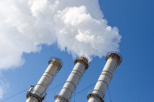 Smoking pipes making clouds against blue sky background. Dioxide air contamination. Environmental pollution