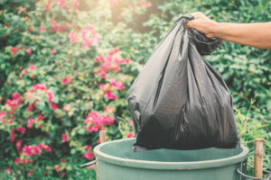 Old hand holding plastic bag in to trash
