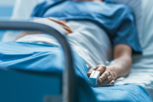 In the Hospital Sick Male Patient Sleeps on the Bed. Heart Rate Monitor Equipment is on His Finger.