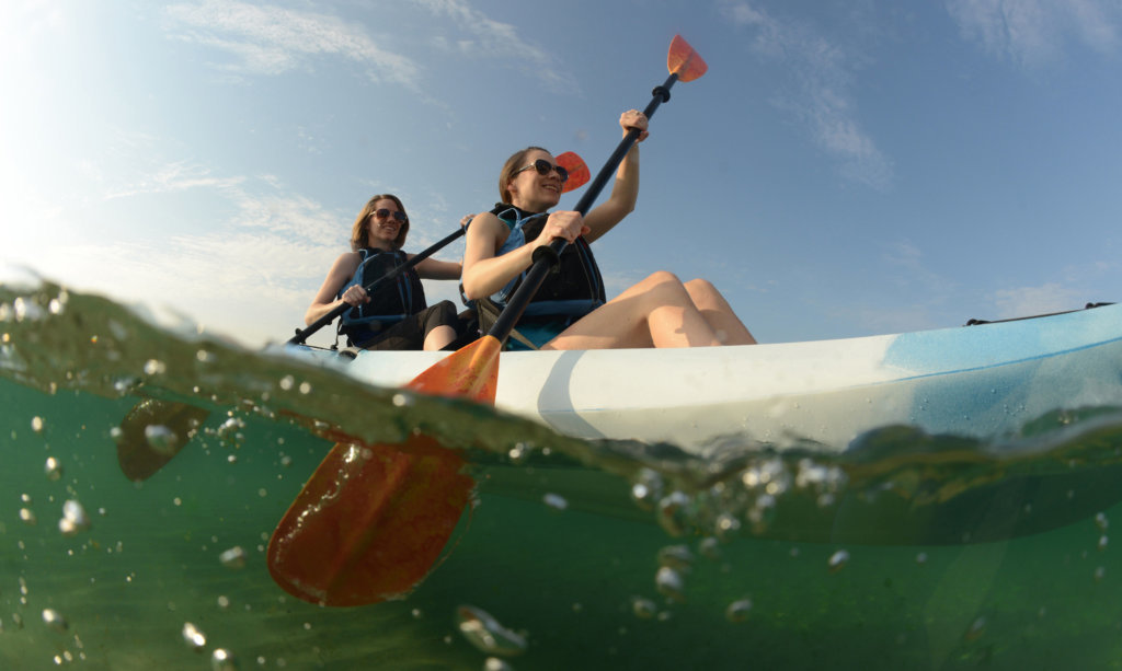Two young women paddling blue kayak