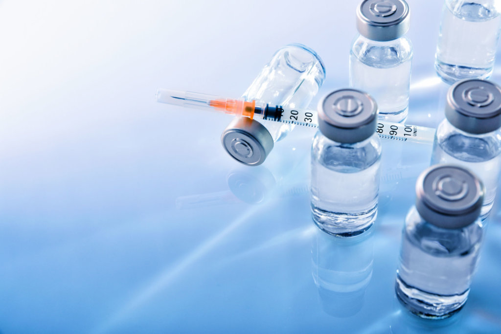 Vials and syringe on blue table top elevated