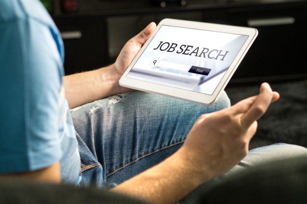 Happy job seeker trying to find work using online search engine home with tablet, Unemployment concept. Hopeful, motivated and excited man, fingers crossed.