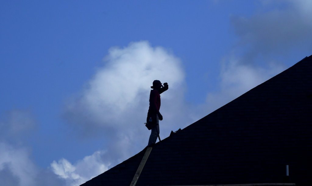 A roofer pauses to wipe his face as he works on a new home under construction Thursday, July 18, 2019, in Houston. A heat wave is expected to send temperatures soaring close to 100 degrees through the weekend across much of the country. The National Weather Service estimates that more than 100 heat records will fall on Saturday. Most will not be the scorching daily highs, but for lack of cooling at night, something called nighttime lows. Those lows will be record highs.