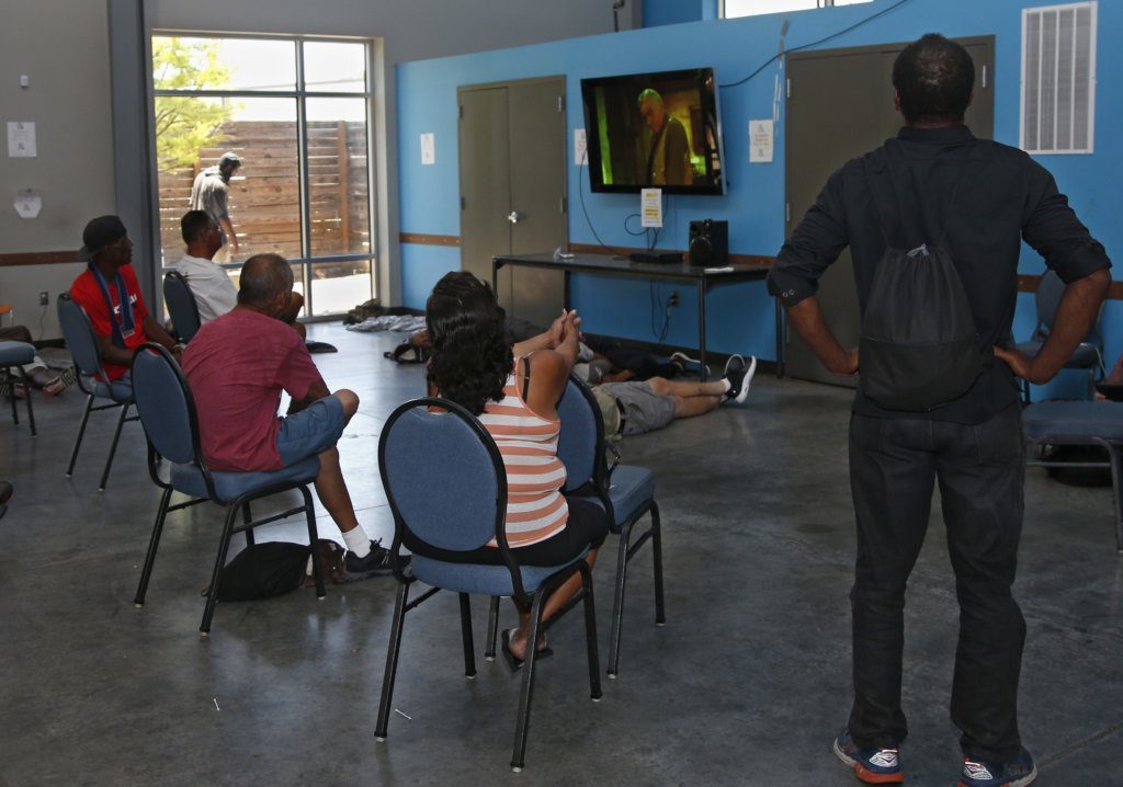 People watch television at the Homeless Alliance day shelter Thursday, July 18, 2019, in Oklahoma City. The air-conditioned day shelter, open from 6 a.m. to 4 p.m., offers breakfast and lunch, provides showers, offers access to computers, phone, and mail, and provides access to mental and physical healthcare, budgeting assistance and legal support. The National Weather Service has issued excessive heat warnings from the Southern Plains to Nebraska and as far east to New York State and parts of the East Coast.
