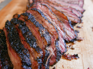 Sliced smoked brisket on a wooden cutting board.