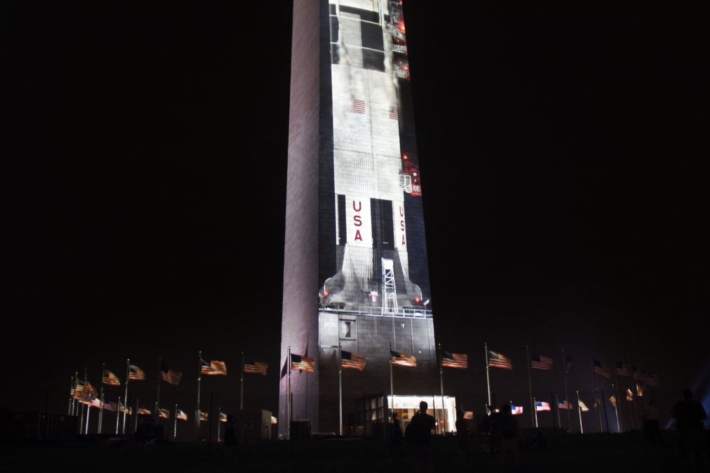 The flags that ring the Washington Monument can be seen as the rocket is projected onto it.