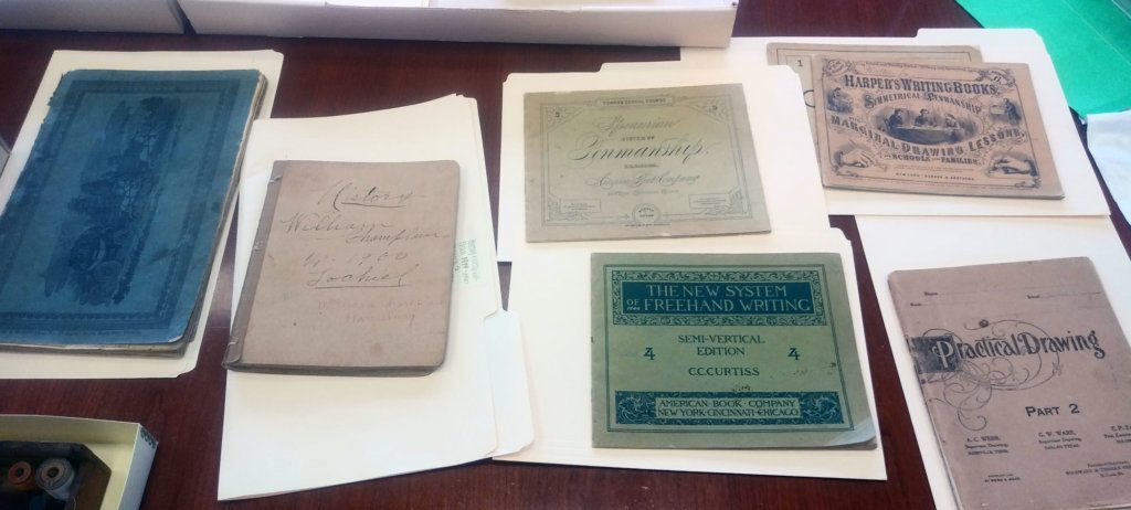 Writing books from the 1840s to 1900s. The blue book on the left is a math book from 1842 that belonged to a young woman. Second from left is a history book from 1900.