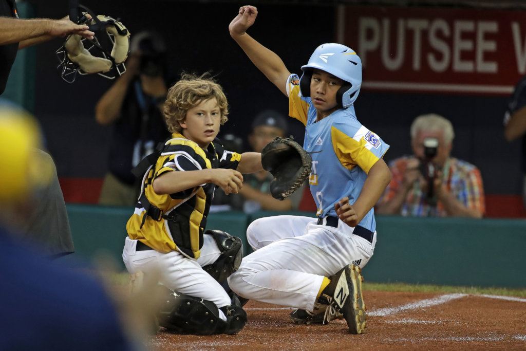 Wailuku, Hawaii's Nakea Kahalehau, right, scores ahead of the tag by South Riding, Va.'s Noah Culpepper during the first inning of a baseball game at the Little League World Series in South Williamsport, Pa., Wednesday, Aug. 21, 2019.