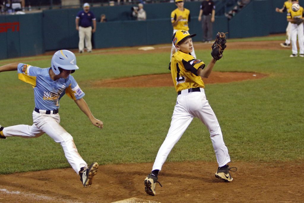 Wailuku, Hawaii's Nakea Kahalehau reaches first base safely as the ball gets away from South Riding, Virginia's first baseman Liam Thyen (8) during the sixth inning of a baseball game at the Little League World Series tournament in South Williamsport, Pa., Wednesday, Aug. 21, 2019.
