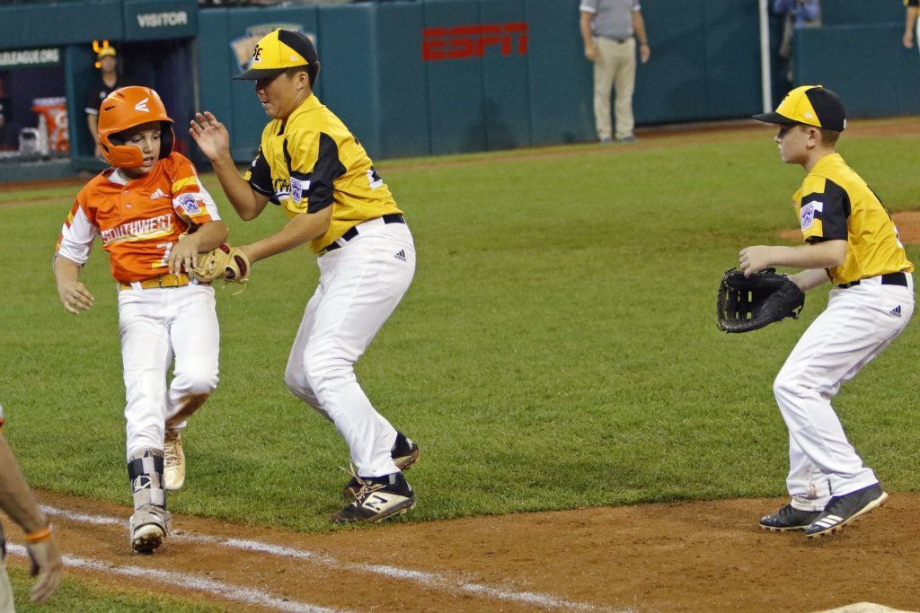 South Riding, Virginia's pitcher Justin Lee tags out River Ridge, Louisiana's Derek DeLatte (7) before he reaches first base as first baseman Matt Coleman, left, watches during the third inning of a baseball game at the Little League World Series tournament in South Williamsport, Pa., Thursday, Aug. 22, 2019. River Ridge, Louisiana won the game 10-0.