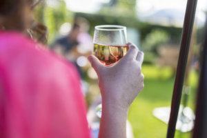 Dark haired woman drinking wine at a summer get together in the UK